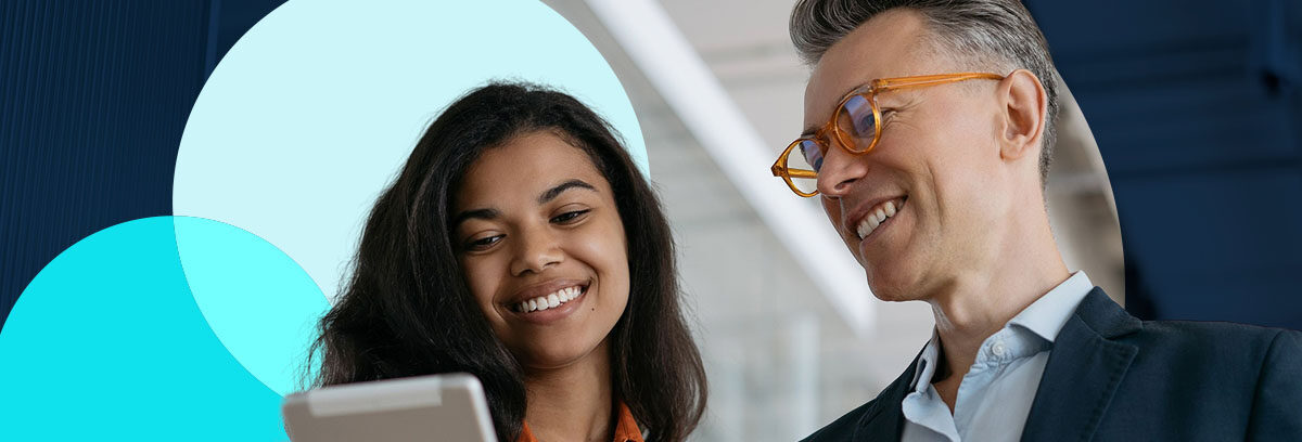 man and women smiling while looking at ipad